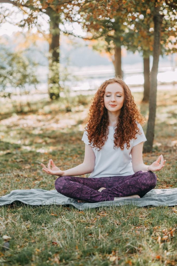 Photo d'une jeune femme rousse en tailleur qui fait de la relaxation et de la méditation