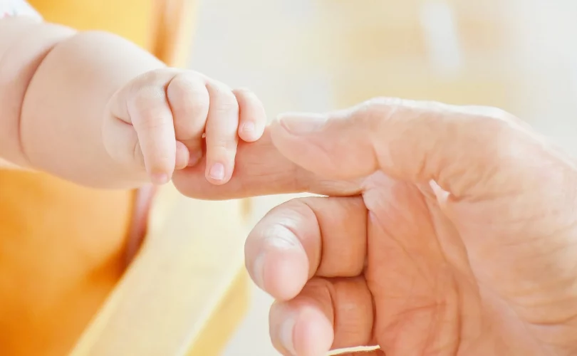 Moi-peau. Photo d'une main de bébé qui tient le doigt de son papa
