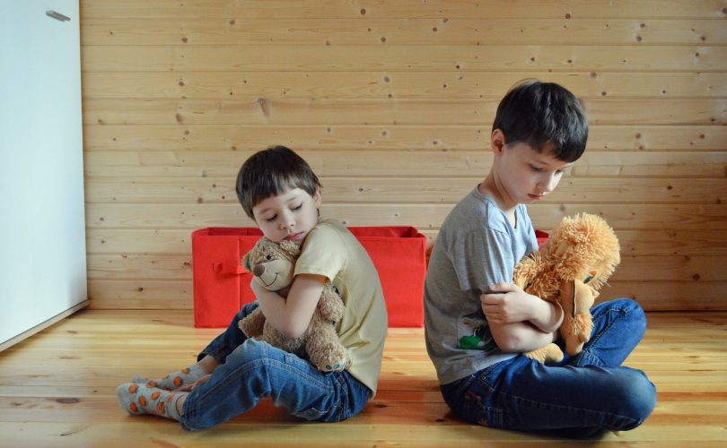 le pardon : photo de deux enfants, frères, qui se font la tête, assis dos à dos
