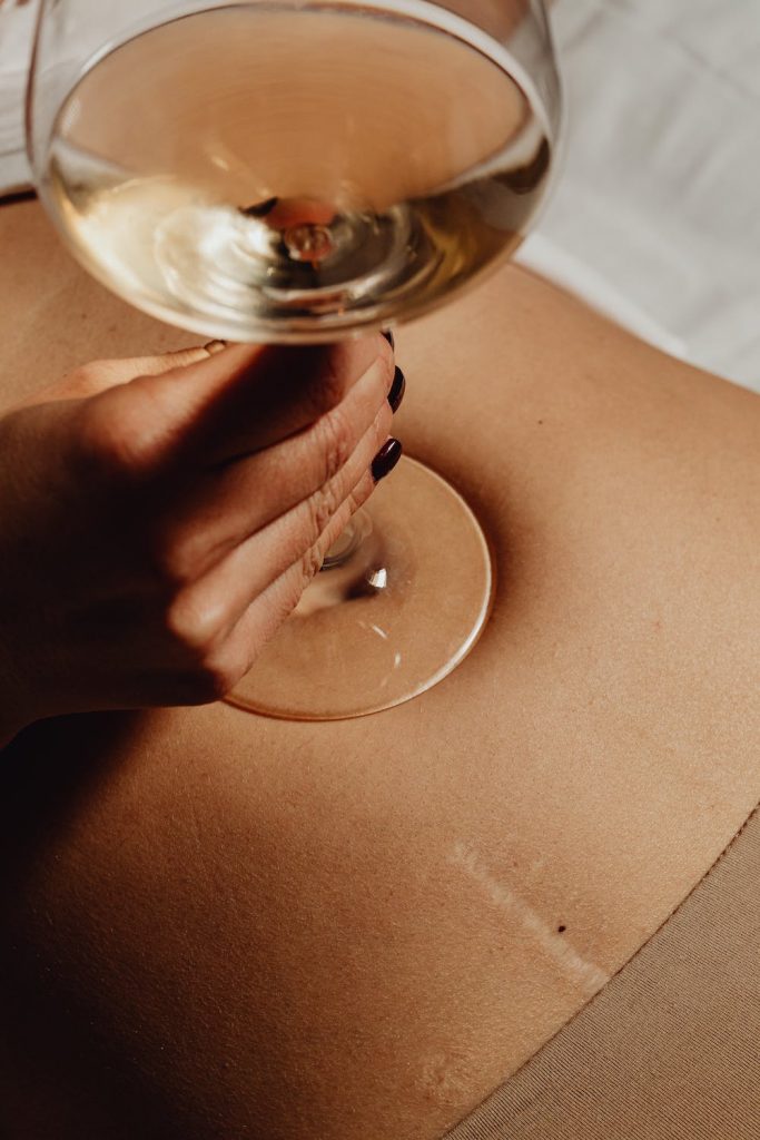 Photo du ventre d'une femme avec un verre de vin. Body positivity