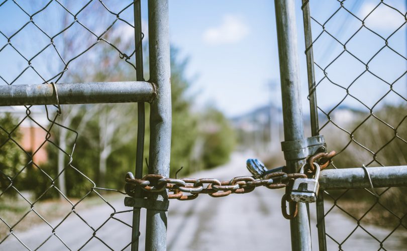 Photo d'une barrière en grillage, fermée par une chaine avec un cadenas. Cela symbolise les croyances limitantes