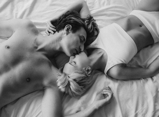 Sexualité : photo en noir et blanc d'un couple en sous-vêtements en train de s'embrasser sur un lit