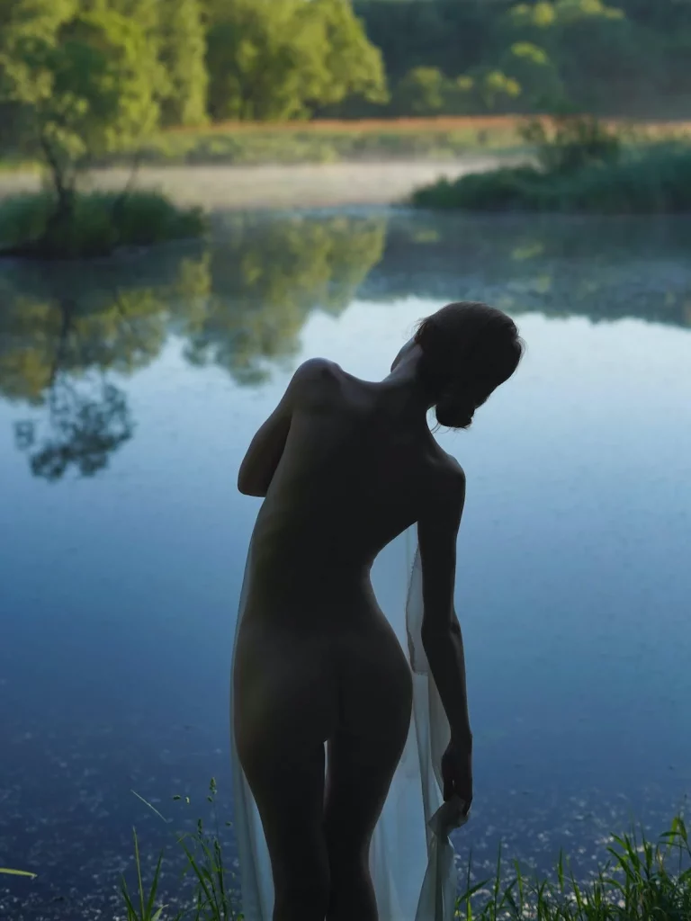 Sexualité : photo d'une femme nue, couverte d'un voile transparent et courbée sur le côté, en tain d'aller dans un lac