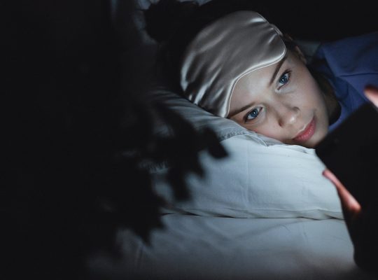 hpi et sommeil : photo d'une jeune fille dans son lit, éveillée et en train d'utiliser son téléphone