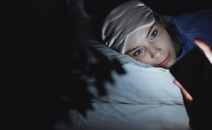 hpi et sommeil : photo d'une jeune fille dans son lit, éveillée et en train d'utiliser son téléphone