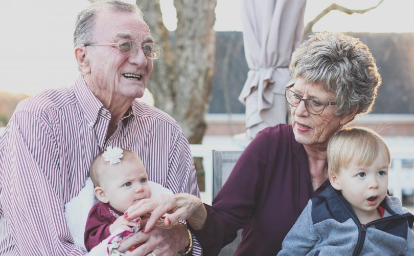 Un grand père et une grand mère montrant leurs sentiments à leurs deux petits enfants en les câlinant