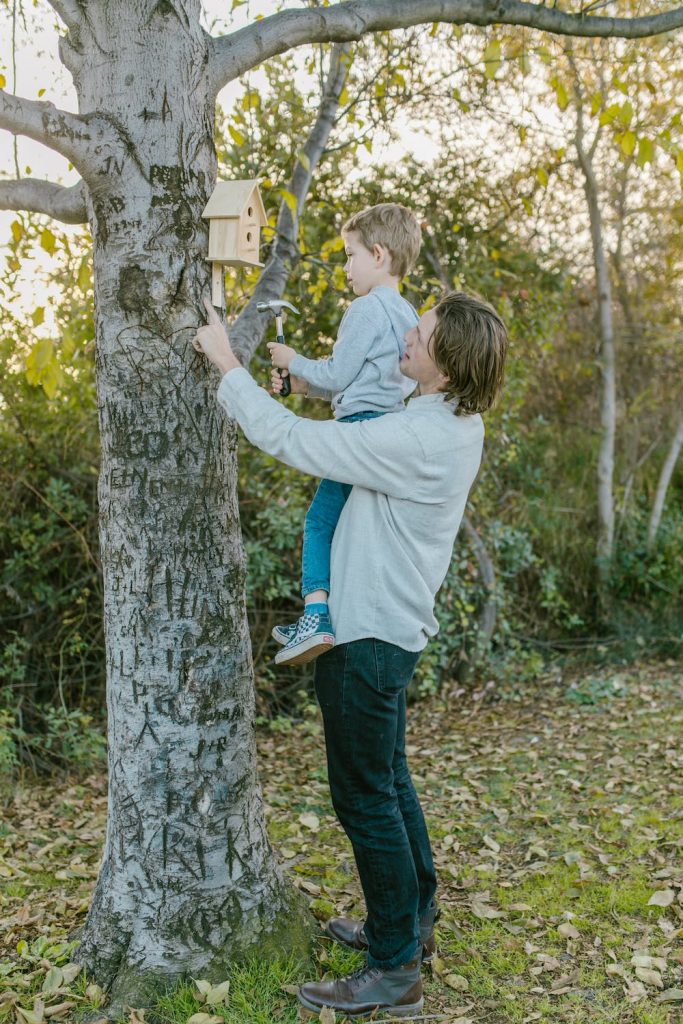 photo d'un papa en train de faire l'instruction en famille avec son fils, en lui faisant installer un nid d'oiseau en bois