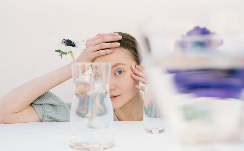 Neuroatypiques : photo d'une jeune femme neuroatypique en train de regarder au travers d'objets en verre