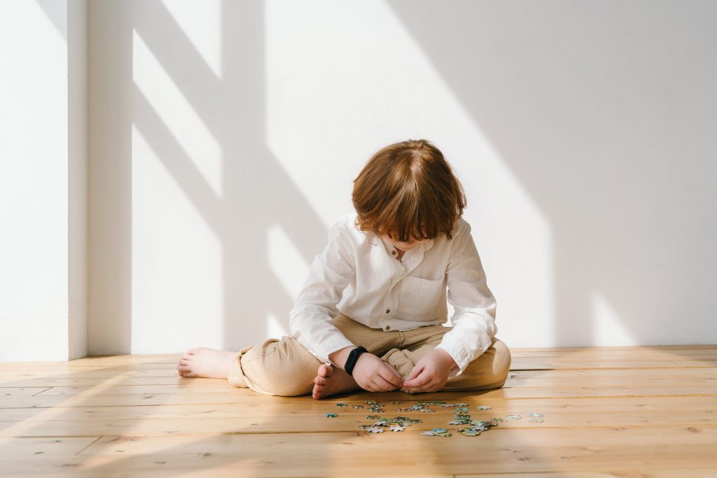 neuroatypiques : photo d'un jeune enfant roux, en train de réaliser seul un puzzle