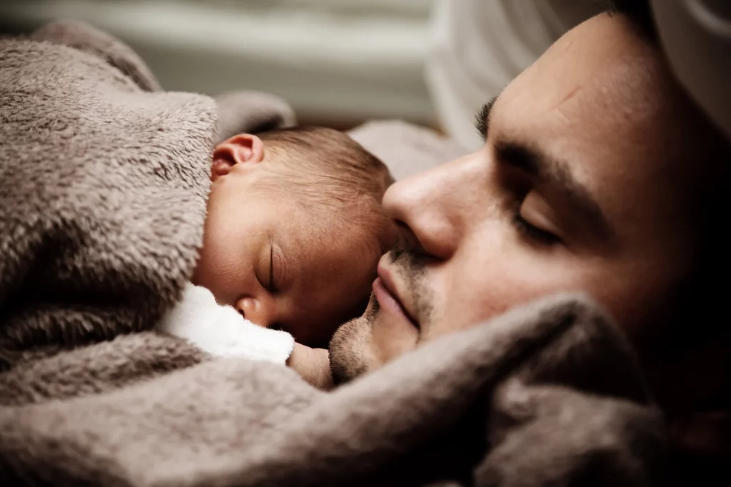 Thérapie existentielle : photo en gros plan d'un papa dormant avec son bébé nouveau né sur lui