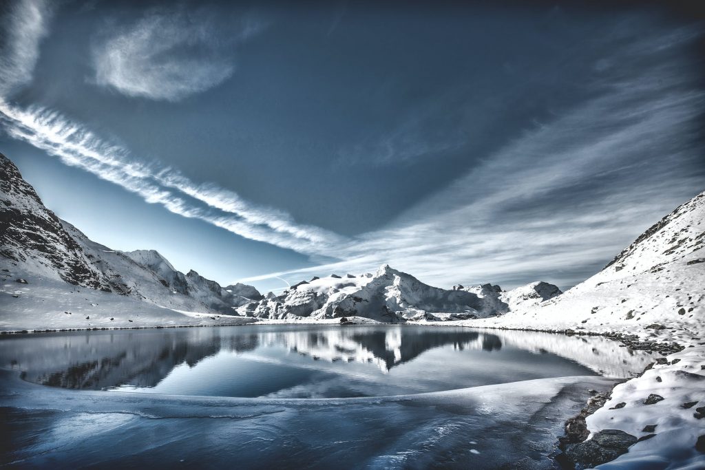Photo d'un paysage sous la neige avec un lac entouré de montagnes, parfait pour la méthode Wim Hof