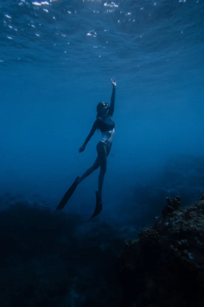 Photo d'une femme sous l'eau en train de remonter à la surface, et qui pratique l'écothérapie