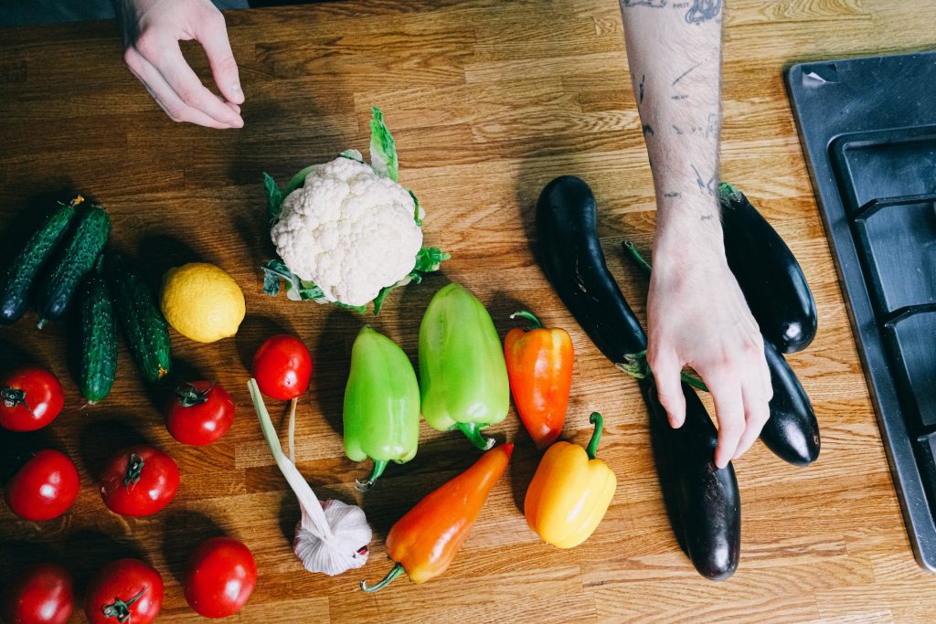 Photo en gros plan des mains d'un homme tatoué, en train de cuisiner des légumes pour lutter contre ses troubles alimentaires.