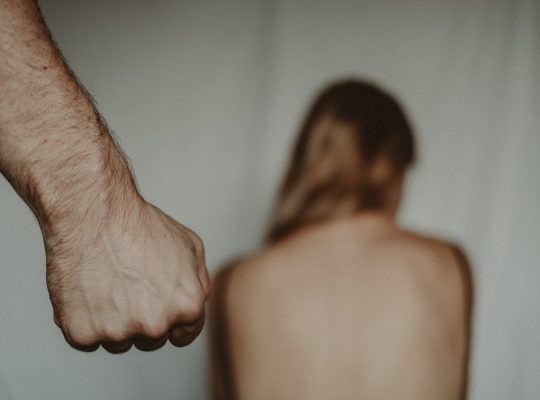 Photo d'une femme nue, de dos, et du poing d'un homme s'approchant d'elle : c'est une scène de viol conjugal.