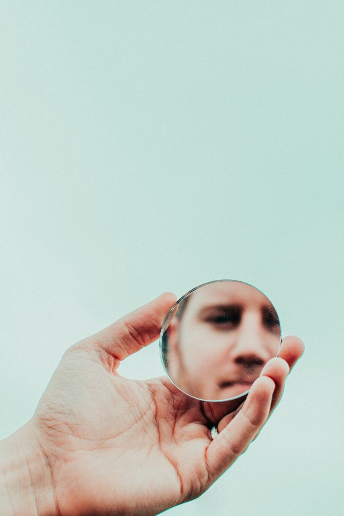 Photo d'un adulte HP barbu qui se regarde dans un miroir de poche pour travailler sur son ego