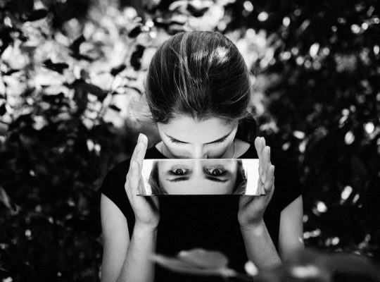 Photo en noir et blanc d'une fille HP qui travaille son ego en se regardant dans un miroir