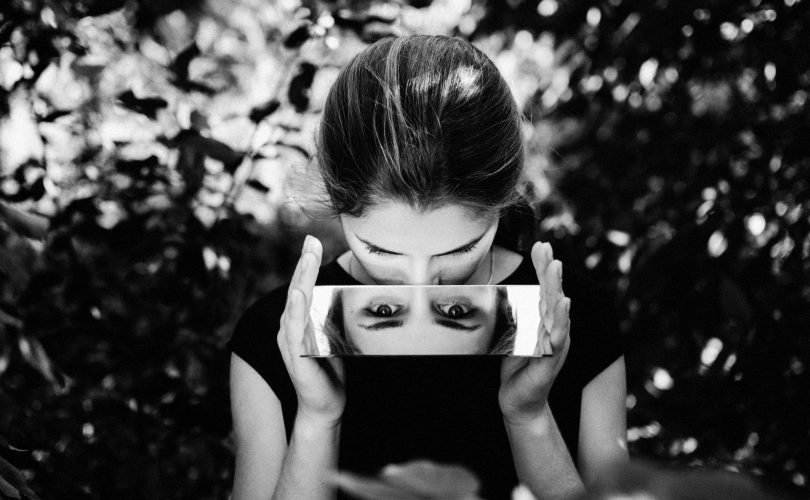 Photo en noir et blanc d'une fille HP qui travaille son ego en se regardant dans un miroir